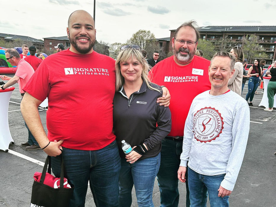 Signature Performance team members posing together at an outdoor event